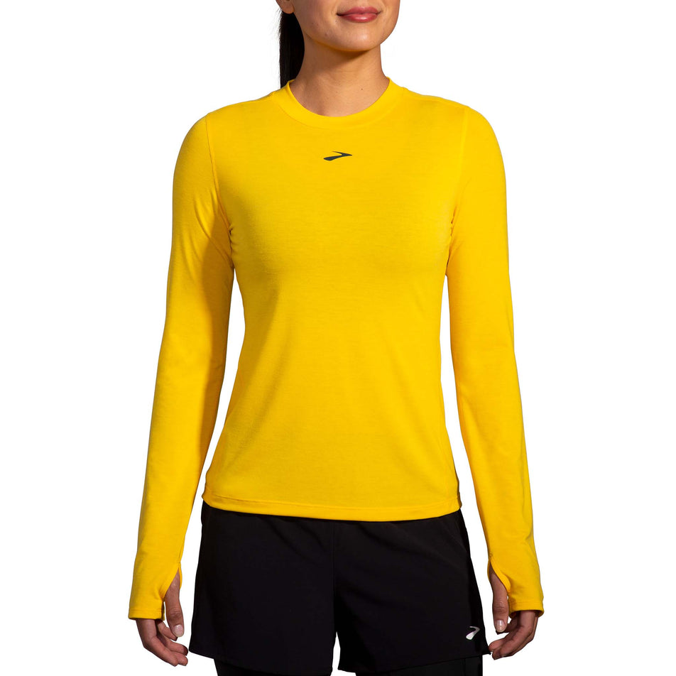Front view of a model wearing a Brooks Women's High Point Long Sleeve Top in the Lemon Chrome colourway. Model is also wearing Brooks legwear.  (8177458249890)