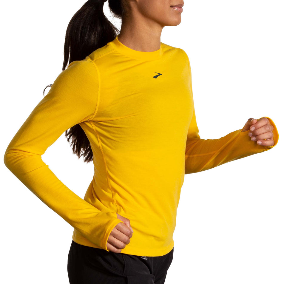Side view of a model wearing a Brooks Women's High Point Long Sleeve Top in the Lemon Chrome colourway. Model is also wearing Brooks legwear. (8177458249890)