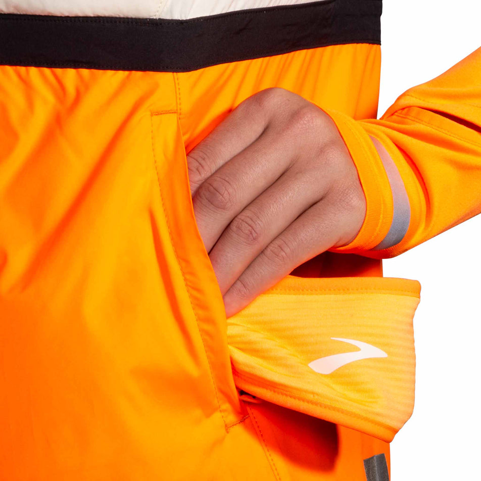 One of the side pockets on the Brooks Women's Run Visible Insulated Vest 2.0 in the Ecru/Fluoro Flash/Black colourway. (8778453483682)
