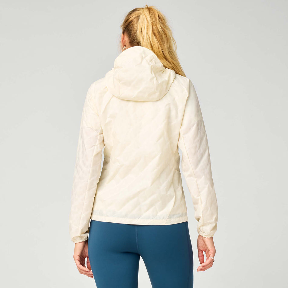 Back view of a model wearing the Brooks Women's Canopy Reflective Jacket in the Reflective Wordmark Bone colourway.