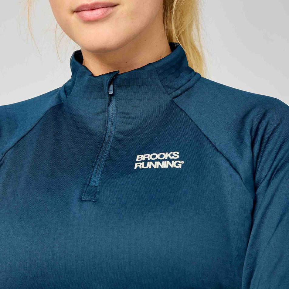 Front view of a model wearing the Brooks Women's Thermal Reflective 1/2 Zip in the Indigo/Reflective colourway.
