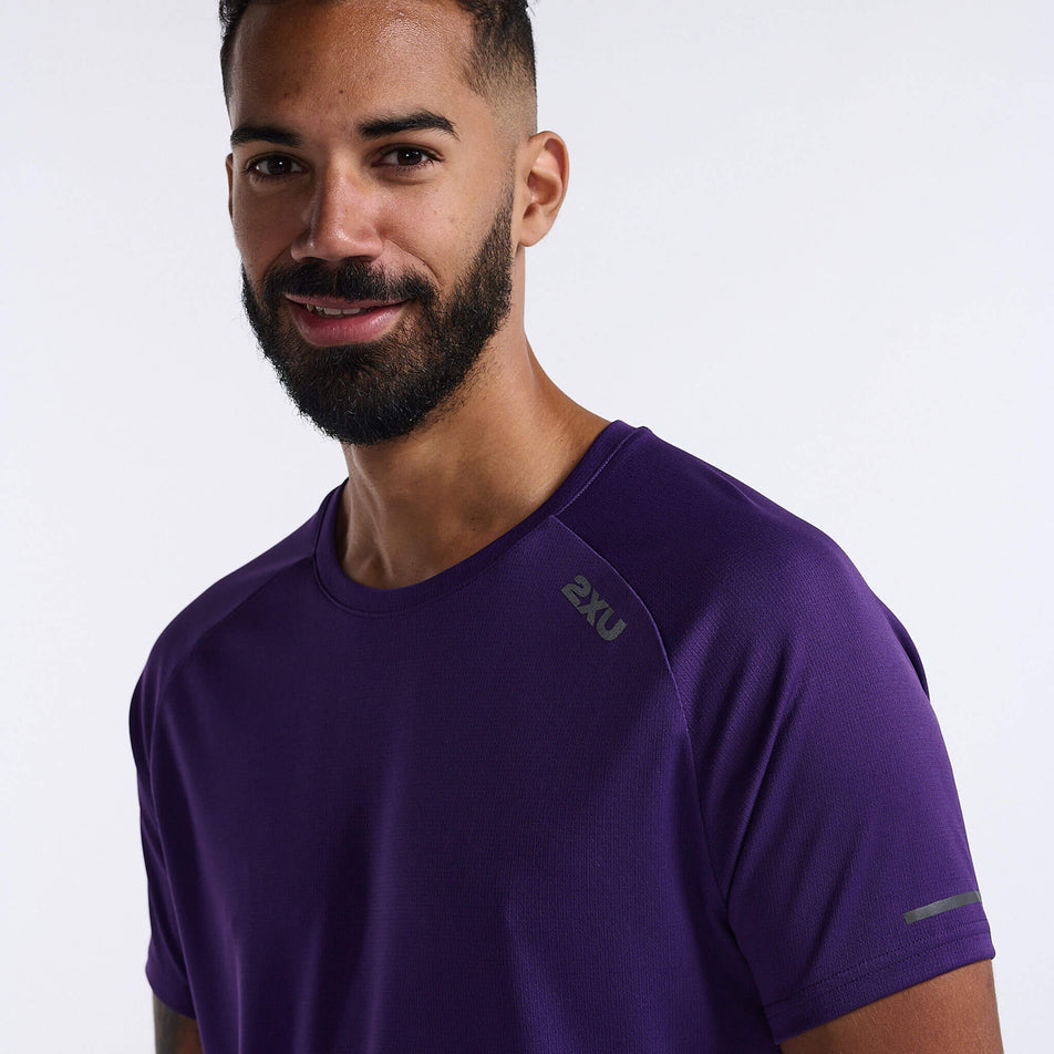 Close-up angled front view of a model wearing a 2XU Men's Aero Tee in the Acai/Black Reflective colourway. Only the top section of the t-shirt can be seen in the image. (8248600920226)