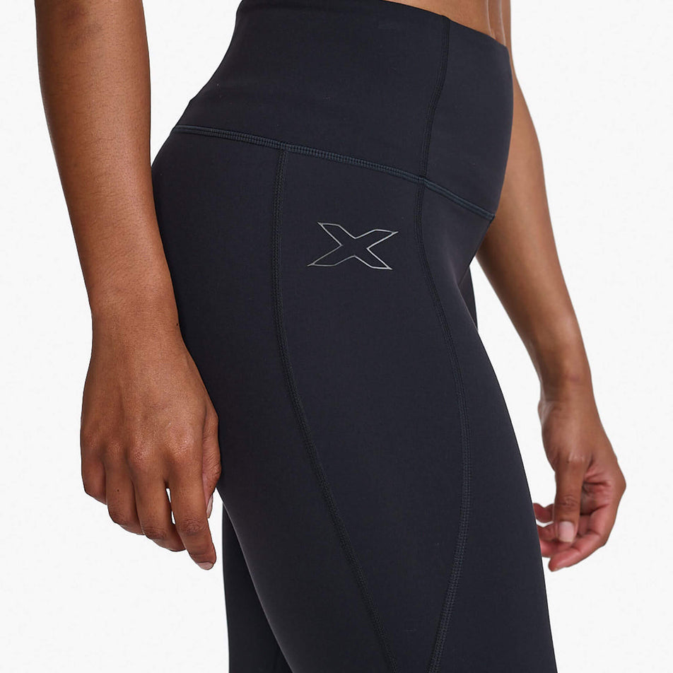 Close-up right-side view of a model wearing a pair of 2XU Women's Form Hi-Rise Compression Tights in the Black/Black colourway. The upper section of the tights can be seen in the image. (8248604262562)