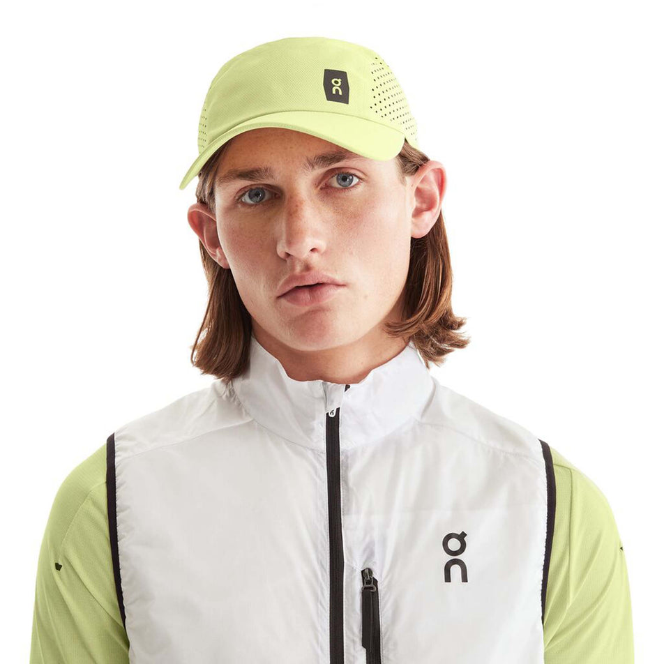 Front view of a model wearing an On Unisex Lightweight Cap in the Hay colourway. On logo is visible. (8008510144674)
