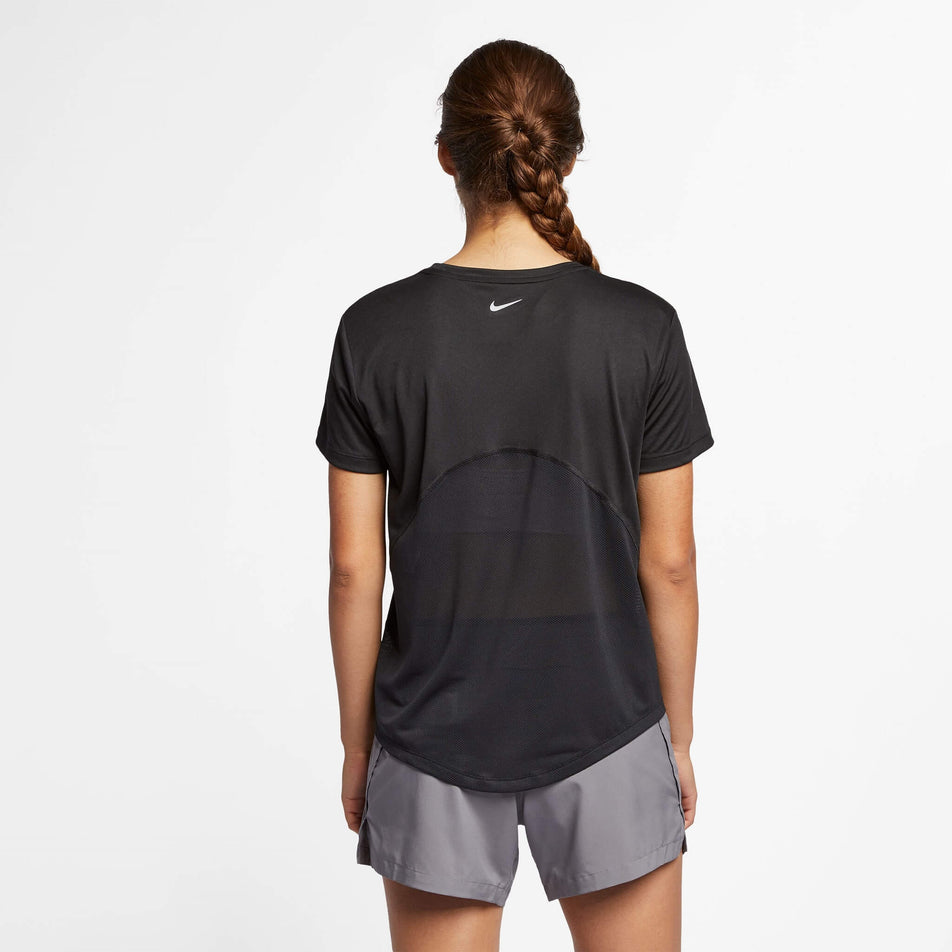 Back view of a model wearing a Nike Women's Miler Short-Sleeve Running Top in the Black/Reflective Silv colourway. Model is also wearing Nike running shorts. (8140153487522)