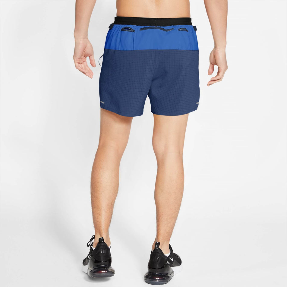 Back view of a model wearing a pair of Nike Men's Dri-FIT Flex Stride Trail Shorts in the Hyper Royal/Midnight Navy/Citron Pulse colourway. Model is also wearing Nike shoes. (8140183535778)