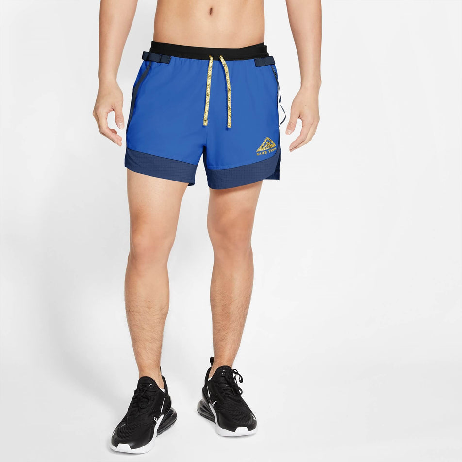 Front view of a model wearing a pair of Nike Men's Dri-FIT Flex Stride Trail Shorts in the Hyper Royal/Midnight Navy/Citron Pulse colourway. Model is also wearing Nike shoes. (8140183535778)