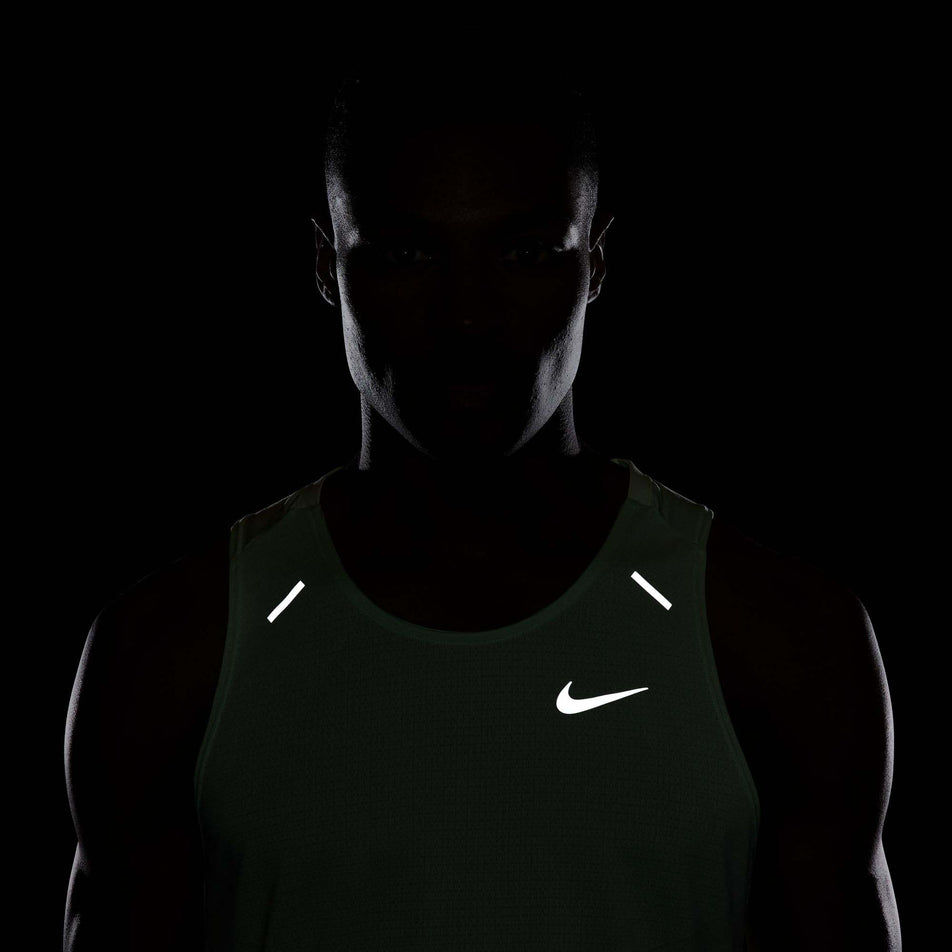 The reflective details, including the reflective Nike Swoosh, which are on the top part of a Nike Men's Rise 365 Dri-FIT Running Tank in the Vapor Green/Reflective Silv colourway.  The top is being worn by a model. (8215870767266)
