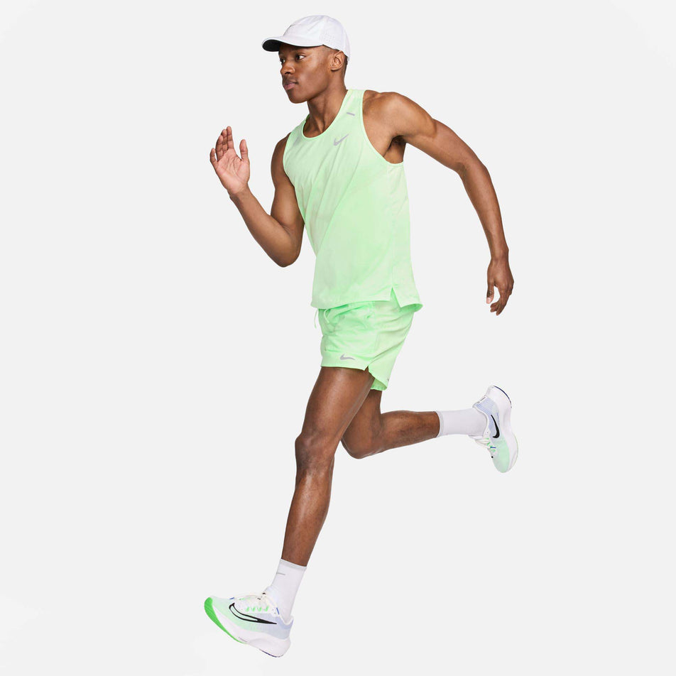 Front view of a model wearing a Nike Men's Rise 365 Dri-FIT Running Tank in the Vapor Green/Reflective Silv colourway. Model is in a running motion and is also wearing Nike socks, shoes, shorts, and a cap. (8215870767266)
