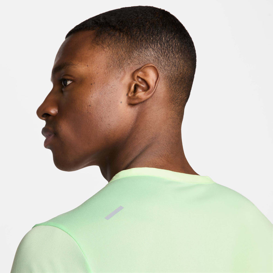 Close-up back view of a model wearing a Nike Men's Rise 365 Dri-FIT Short-Sleeve Running Top in the Vapor Green/Reflective Silv colourway. Only the upper part of the top can be seen in the image. (8215872766114)