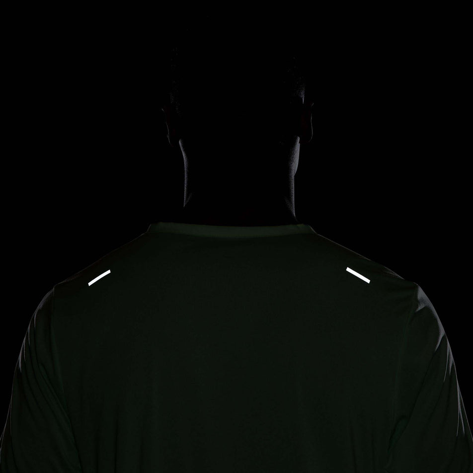 Back view of the reflective details on the upper part a Nike Men's Rise 365 Dri-FIT Short-Sleeve Running Top in the Vapor Green/Reflective Silv colourway. Top is being worn by a model. (8215872766114)
