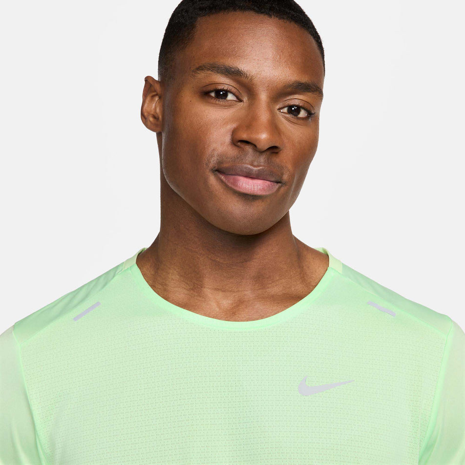 Close-up front view of a model wearing a Nike Men's Rise 365 Dri-FIT Short-Sleeve Running Top in the Vapor Green/Reflective Silv colourway. Only the upper third of the top can be seen in the image. (8215872766114)