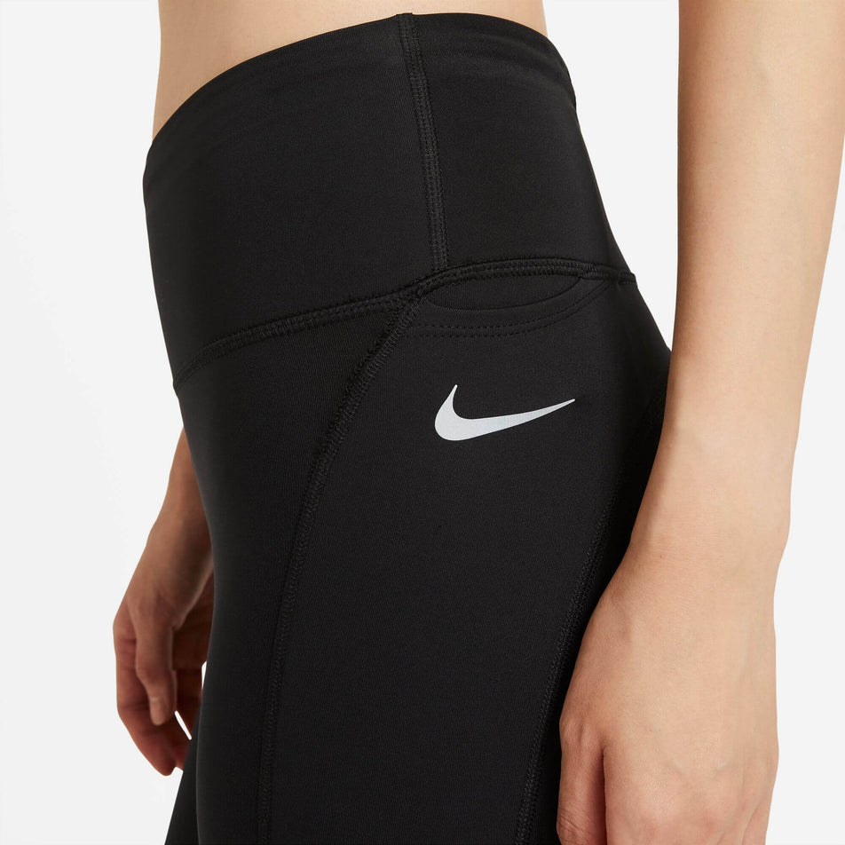Left side view of the waist and hip section of a pair of Nike Women's Epic Fast Mid-Rise Pocket Running Leggings in the Black/Reflective Silv colourway. Leggings are being worn by a model. (8049598562466)