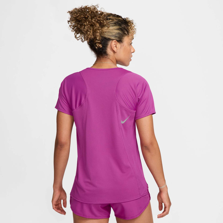 Back view of a model wearing a Nike Women's Dri-FIT Race Short-Sleeve Running Top in the Hot Fuchsia/Reflective Silv colourway. Model is also wearing Nike shorts. (8399187640482)