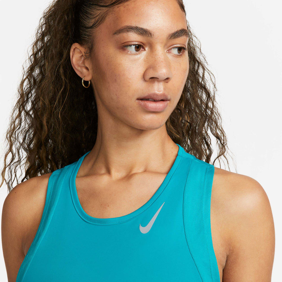 Close-up front view of model wearing a Nike Women's Dri-FIT Race Running Singlet in the Rapid Teal/Reflective Silv colourway. Upper third of the singlet is visible.  (7999728615586)