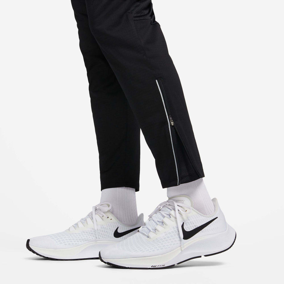 Close-up view of the zip on the outside of the lower left leg of a pair of Nike Men's Phenom Dri-FIT Knit Running Pants in the Black/Reflective SIlv colourway (8049583325346)