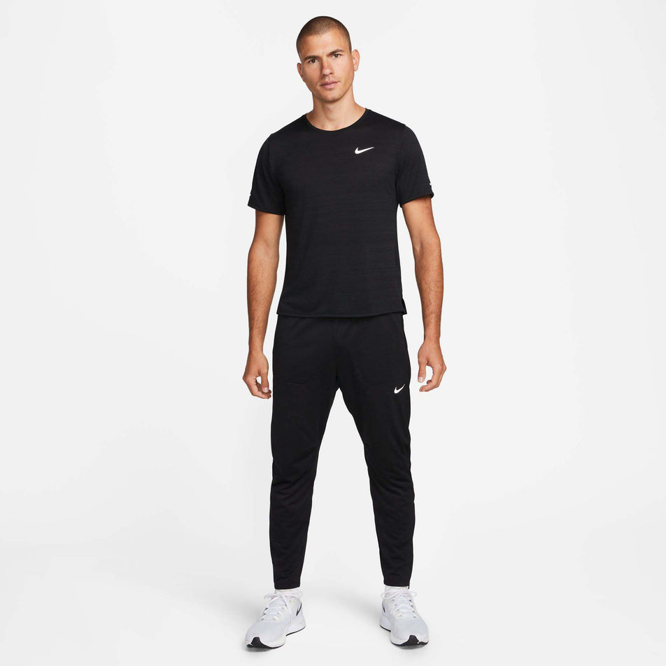Front view of a model wearing a pair of Nike Men's Phenom Dri-FIT Knit Running Pants in the Black/Reflective SIlv colourway. Model is also wearing a Nike running t-shirt and Nike running shoes. (8049583325346)