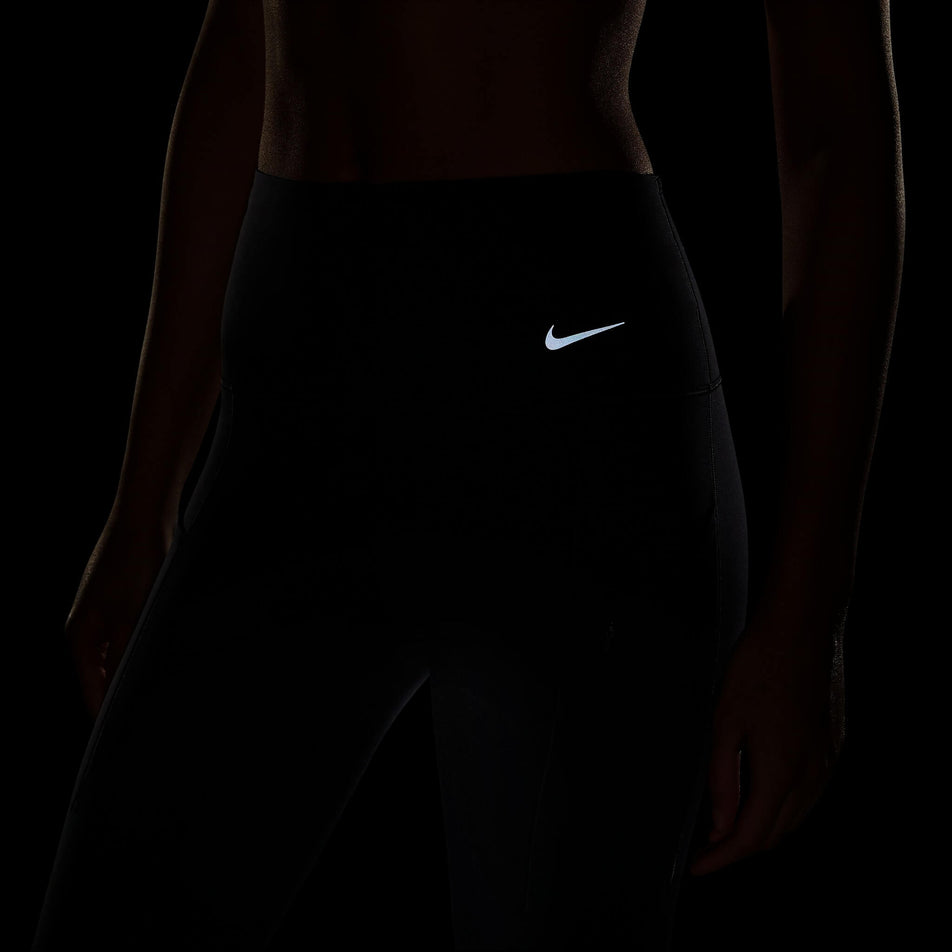 The reflective Swoosh on a pair of Nike Women's Go Firm-Support High-Waisted Full-Length Leggings with Pockets in the Black/Black colourway. Leggings are being worn by a model. (8140163252386)