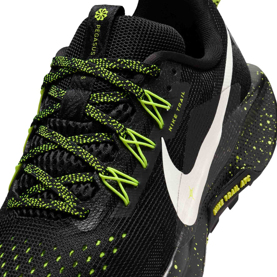 Close-up view of the upper of the left shoe from a pair of Nike Women's Pegasus Trail 5 Running Shoes in the Black/Phantom-Volt Ice colourway.