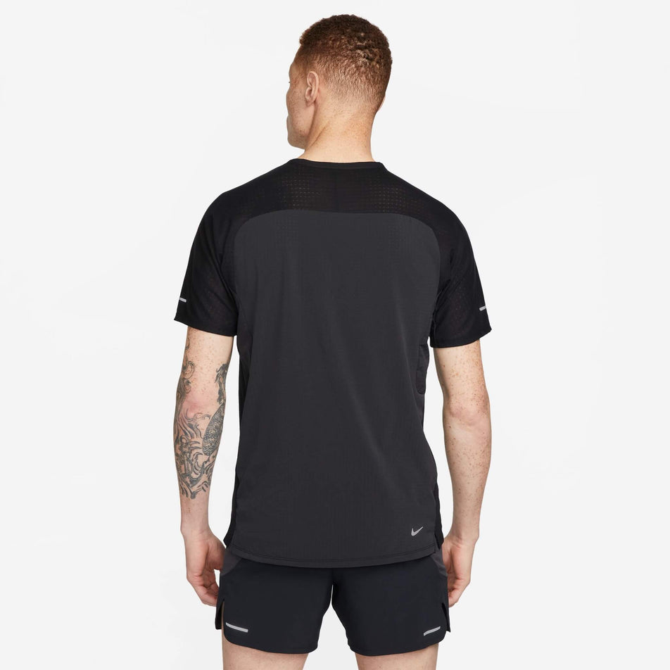 Back view of a model wearing a Nike Men's Trail Solar Chase Dri-FIT Short-Sleeve Running Top in the Black/White colourway. Model is also wearing a pair of Nike shorts. (8140170199202)