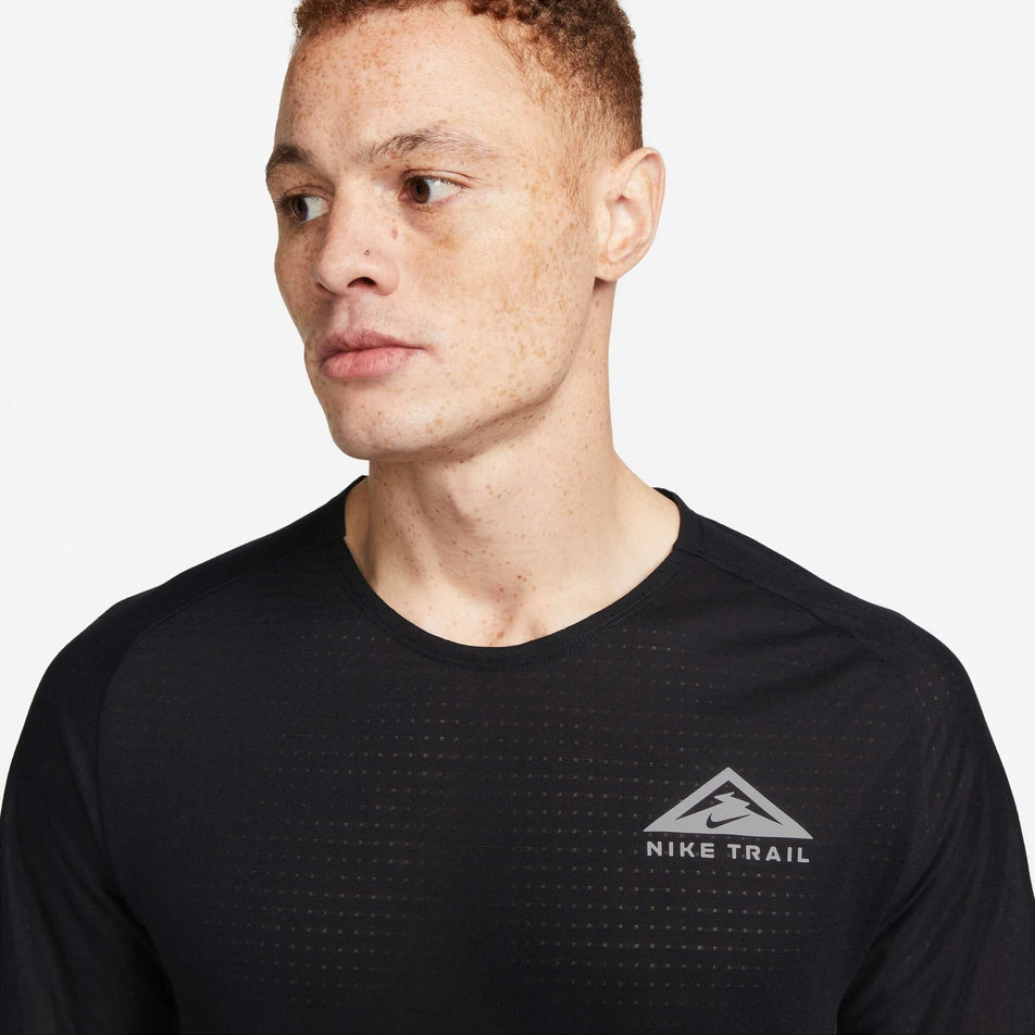 Front view of the upper third of a Nike Men's Trail Solar Chase Dri-FIT Short-Sleeve Running Top in the Black/White colourway. Top is being worn by a model. (8140170199202)