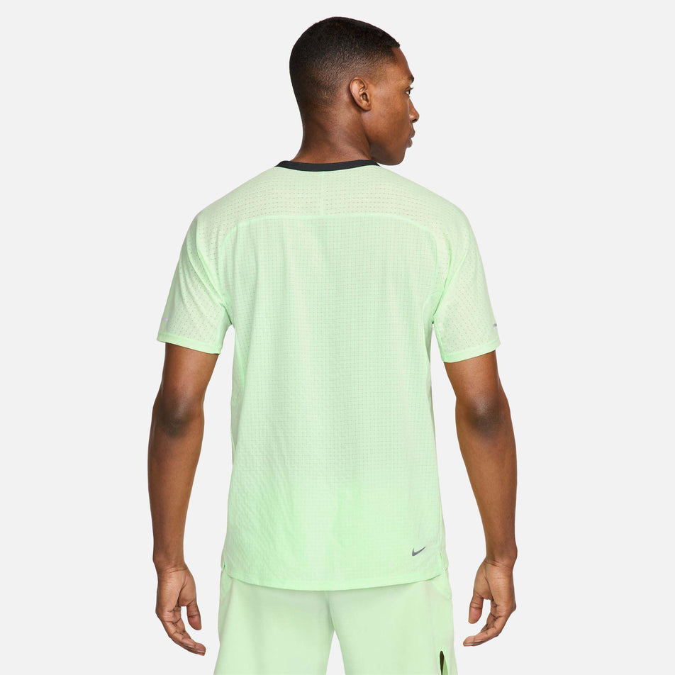 Back view of a model wearing a Nike Men's Trail Solar Chase Dri-FIT Short-Sleeve Running Top in the Vapor Green/Black colourway. Model is also wearing Nike shorts. (8215882825890)