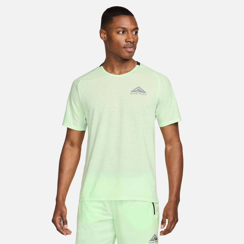 Front view of a model wearing a Nike Men's Trail Solar Chase Dri-FIT Short-Sleeve Running Top in the Vapor Green/Black colourway. Model is also wearing Nike shorts. (8215882825890)
