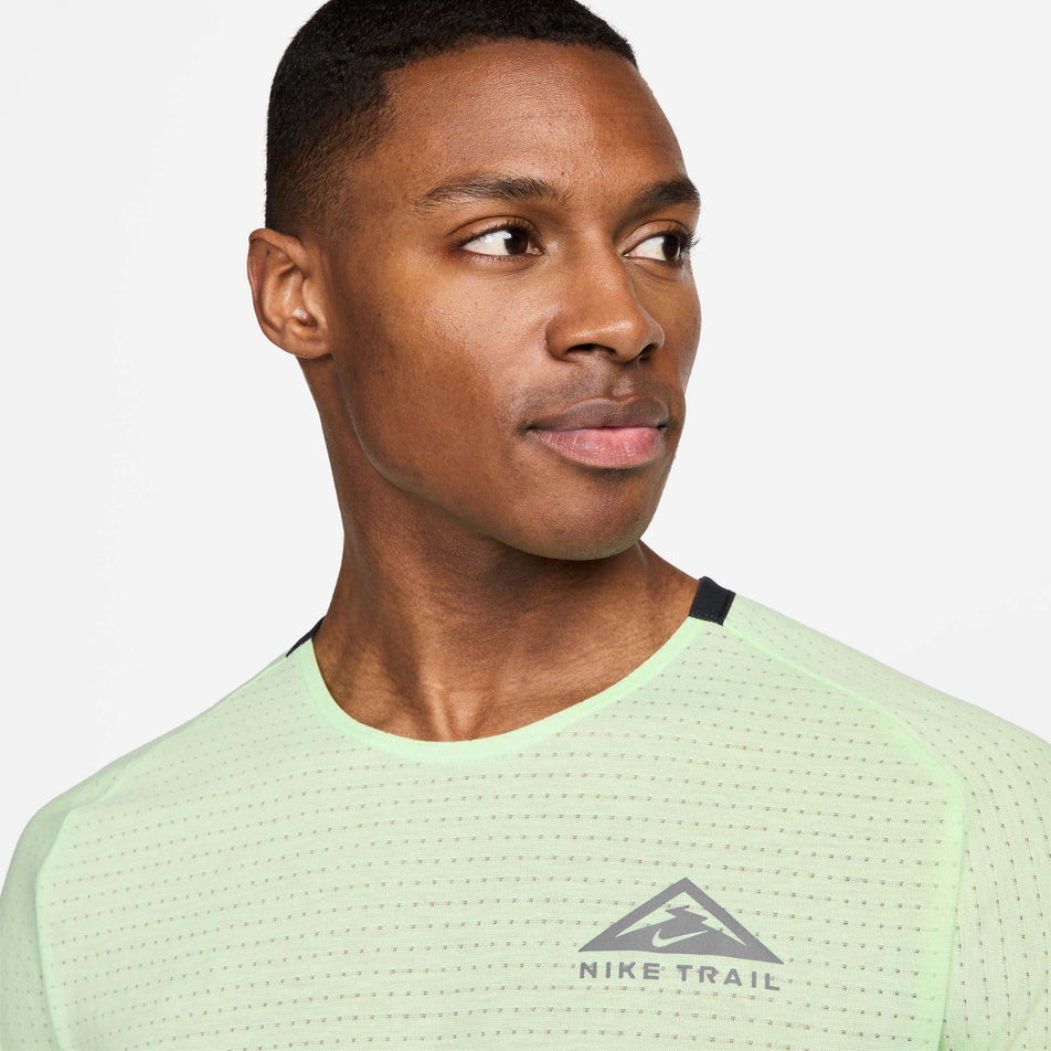 Close-up front view of a model wearing a Nike Men's Trail Solar Chase Dri-FIT Short-Sleeve Running Top in the Vapor Green/Black colourway. Only the upper part of the top is viewable in the image. (8215882825890)