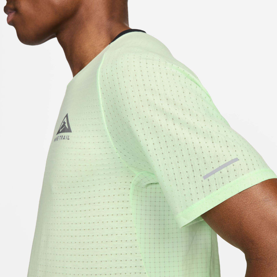 Close-up left side view of a model wearing a Nike Men's Trail Solar Chase Dri-FIT Short-Sleeve Running Top in the Vapor Green/Black colourway. Only the upper part of the top is viewable in the image. (8215882825890)