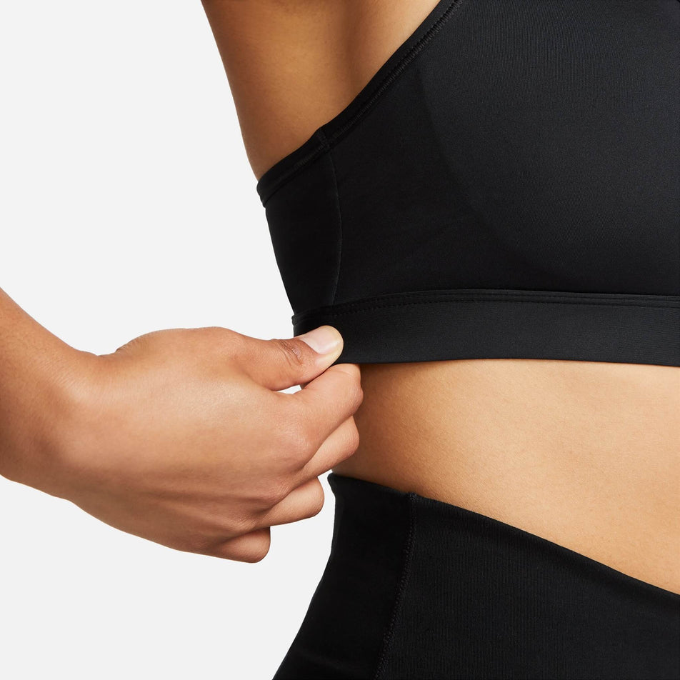 Close-up of the left-side of a Nike Women's Swoosh Medium Support Padded Sports Bra in the Black/White colourway. Bra is being worn by a model. (8140167086242)