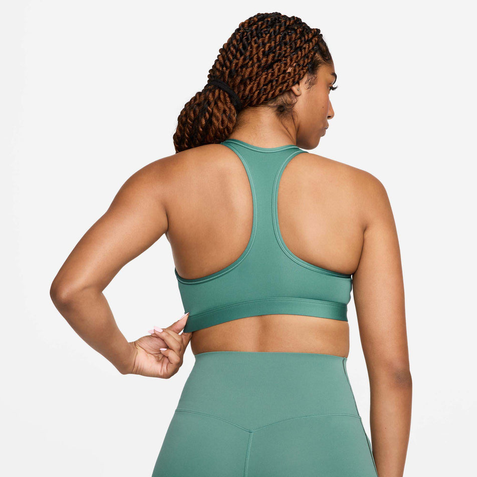 Back view of a model wearing a Nike Women's Swoosh Medium Support Padded Sports Bra in the Bicoastal/White colourway. Model is also wearing Nike leggings. (8299354063010)