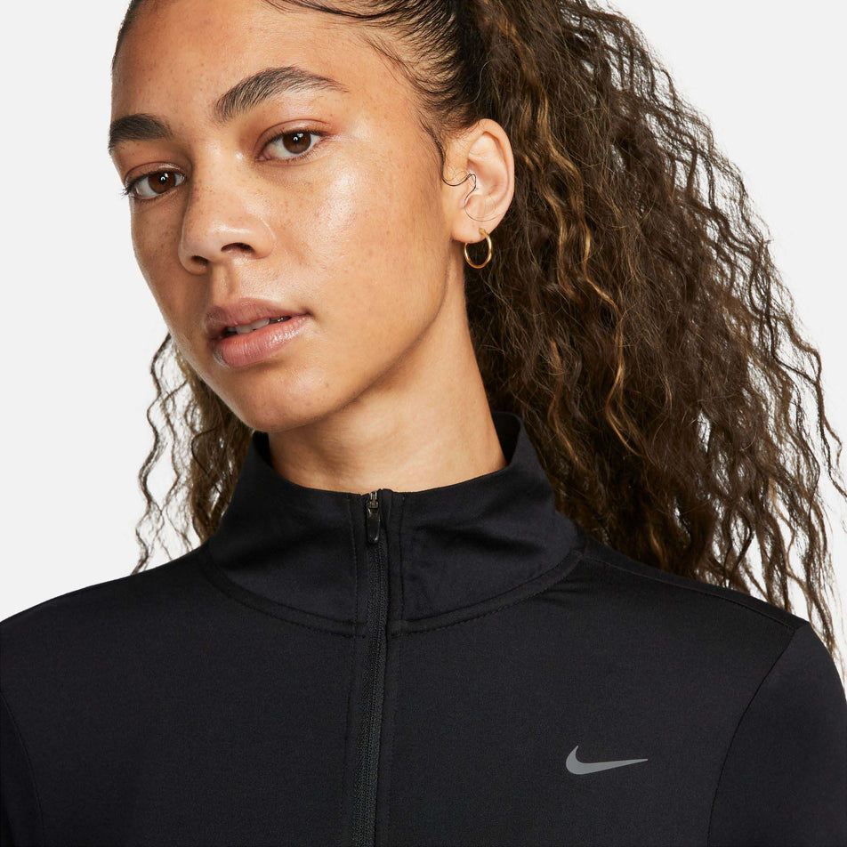 Close-up view of the top third of a Nike Women's Dri-FIT Swift Element UV 1/4-Zip Running Top in the Black/Reflective Silv colourway. Top is being worn by a model. (8049594007714)