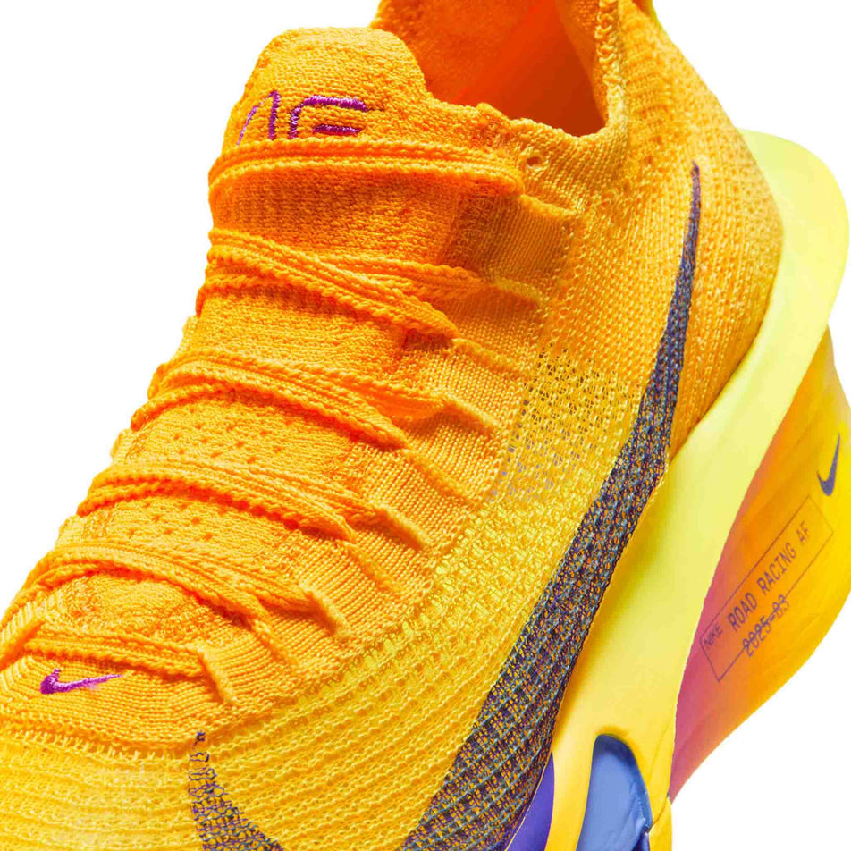 Close-up view of the upper of the left shoe from a pair of Nike Women's Alphafly 3 Road Racing Shoes in the Laser Orange/Indigo Burst-Citron Pulse colourway.