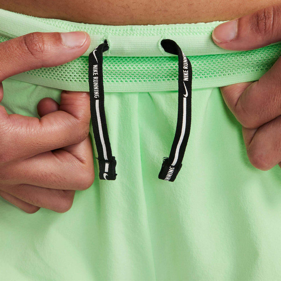 A model highlighting the drawcord on the inside of the waistband on a pair of Nike Women's AeroSwift Dri-FIT ADV Mid-Rise Brief-Lined 3