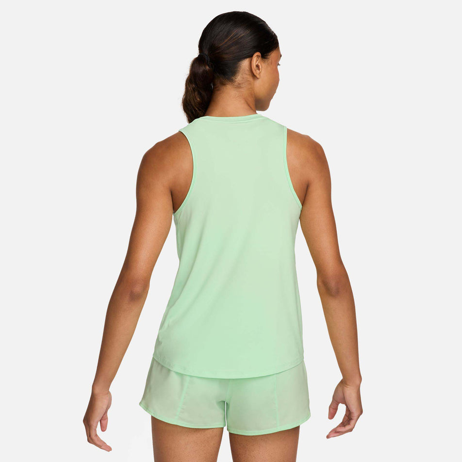 Back view of a model wearing a Nike Women's One Graphic Running Tank Top in the Vapor Green/Bicoastal colourway. Model is also wearing Nike shorts. (8299396104354)