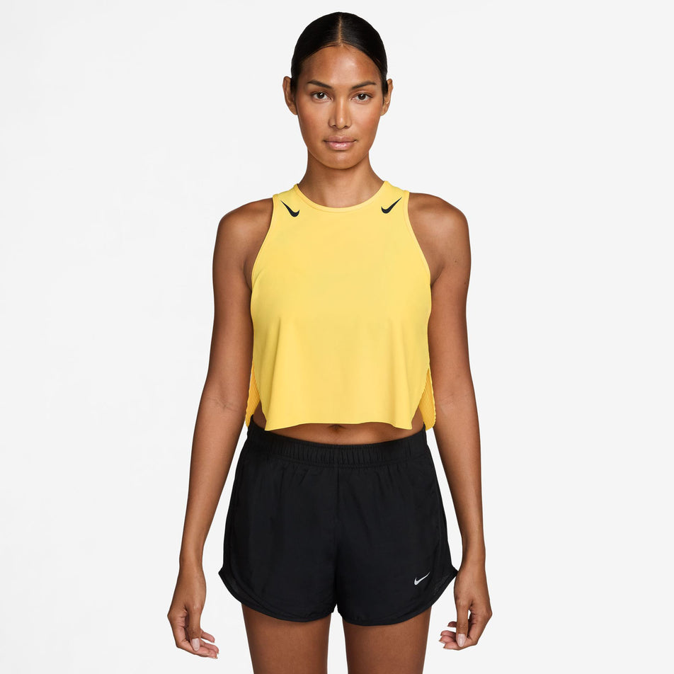 Front view of a model wearing the Nike Women's AeroSwift Dri-FIT ADV Cropped Running Tank Top in the Citron Pulse/Black colourway.