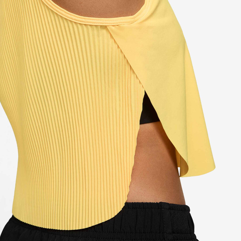 Side view of a model wearing the Nike Women's AeroSwift Dri-FIT ADV Cropped Running Tank Top in the Citron Pulse/Black colourway.