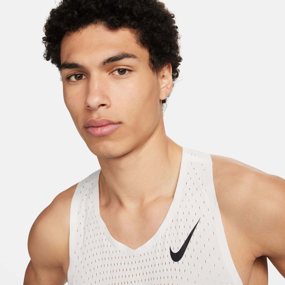 Close-up front view of a model wearing a Nike Men's AeroSwift Dri-FIT ADV Running Singlet in the Summit White/Black colourway. Only the upper section of the singlet can be seen in the image. (8186007322786)
