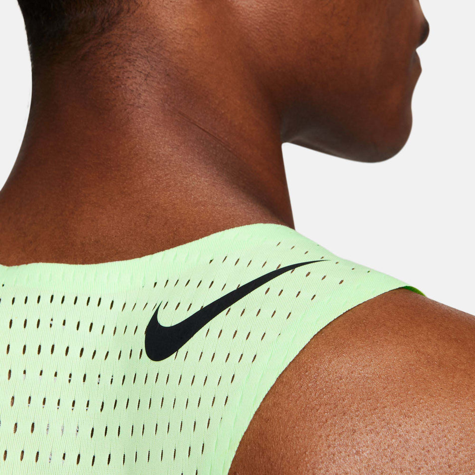 Close-up back view of a model wearing a Nike Men's AeroSwift Dri-FIT ADV Running Singlet in the Vapor Green/Black colourway. Only the upper part of the singlet can be seen in the image. (8186010337442)