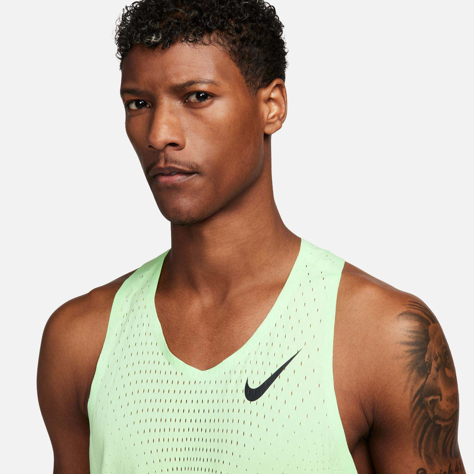 Close-up front view of a model wearing a Nike Men's AeroSwift Dri-FIT ADV Running Singlet in the Vapor Green/Black colourway. Only the upper part of the singlet can be seen in the image. (8186010337442)