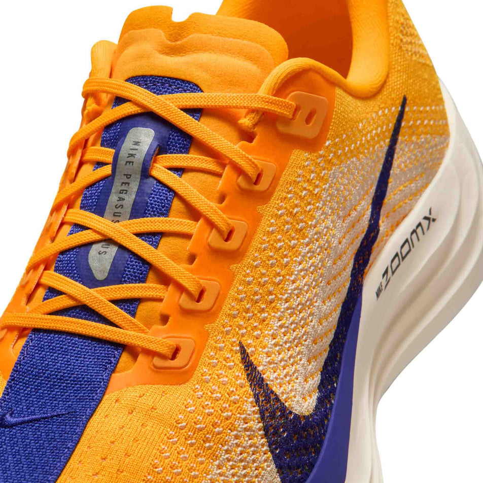 Close-up view of the upper of the left shoe from a pair of Nike Men's Pegasus Plus Road Running Shoes in the Laser Orange/Indigo Burst-Alabaster-Sail colourway.