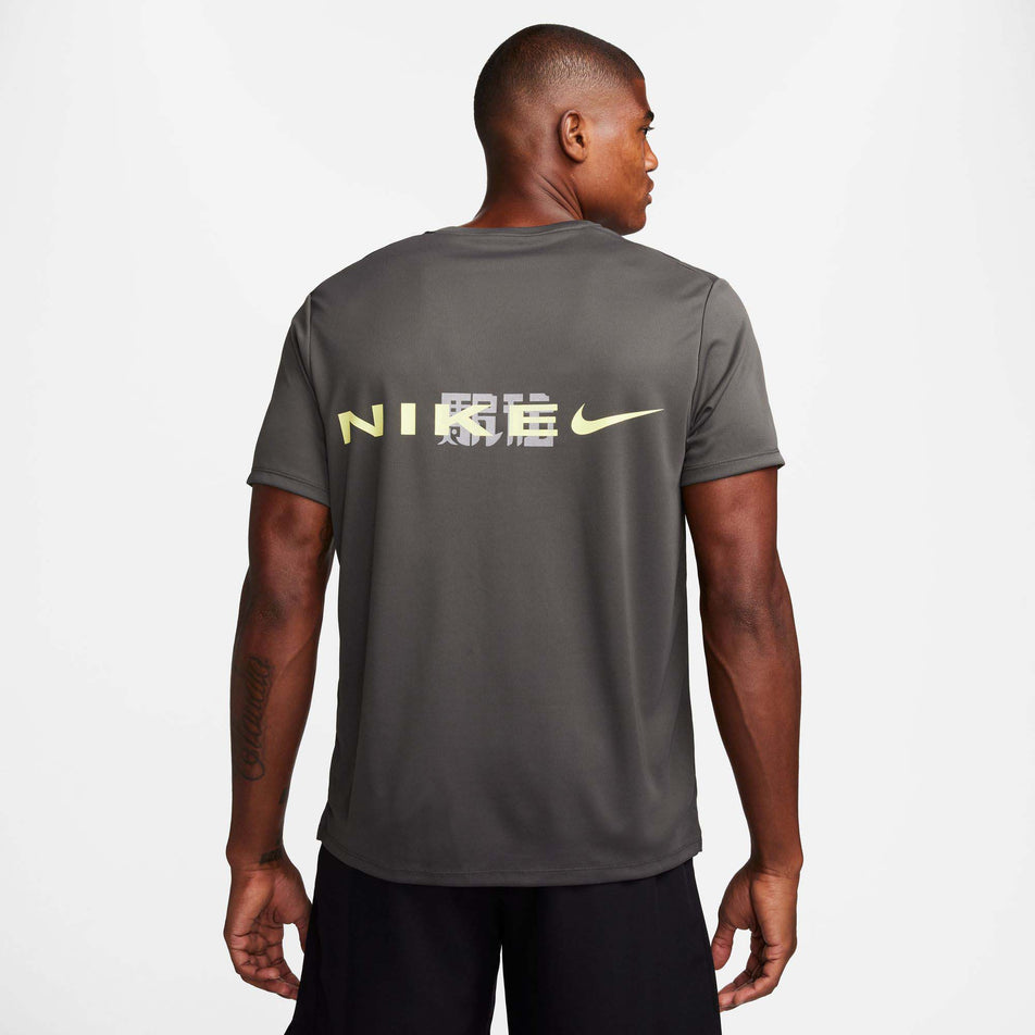 Back view of a model wearing a Nike Men's Miler Dri-FIT UV Short-Sleeve Running Top in the Medium Ash/Luminous Green/Light Bone colourway (8141458473122)