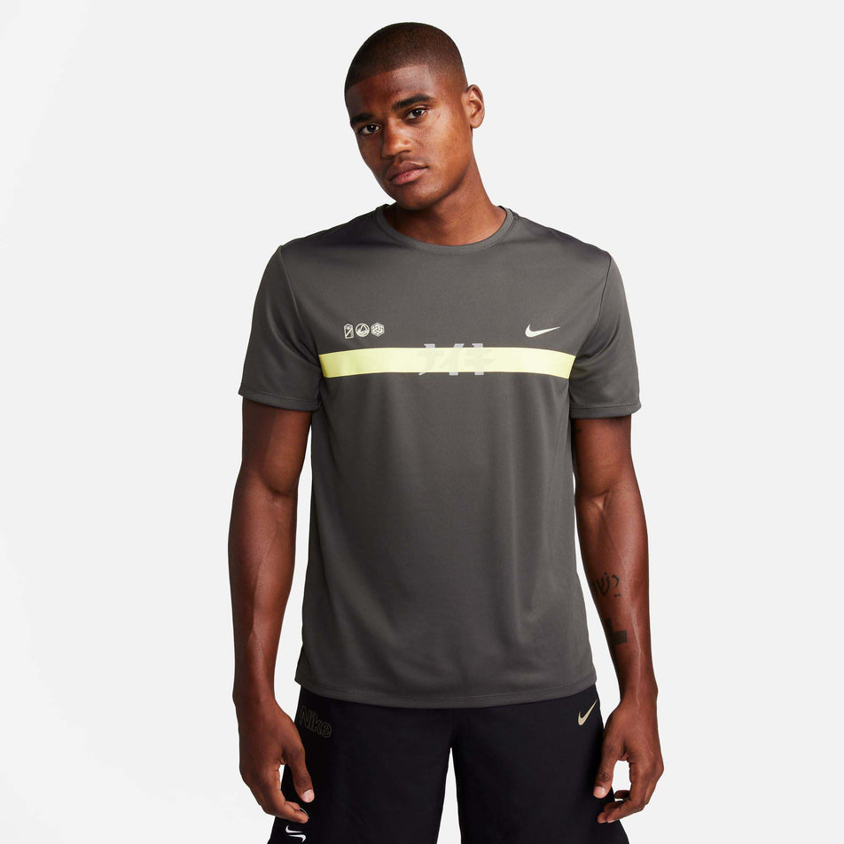 Front view of a model wearing a Nike Men's Miler Dri-FIT UV Short-Sleeve Running Top in the Medium Ash/Luminous Green/Light Bone colourway (8141458473122)