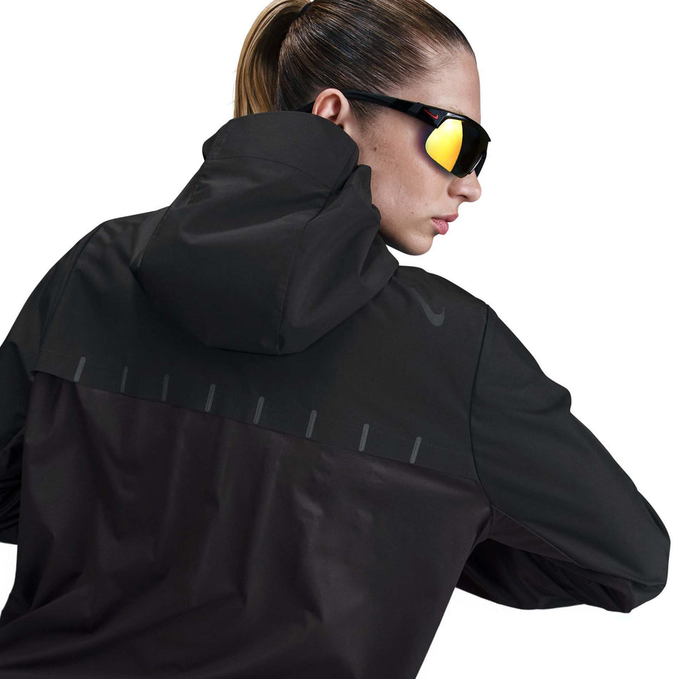 Back view of a model wearing the Nike Women's AeroSwift Aerogami Storm-FIT Running Jacket in the Black/Black colourway.