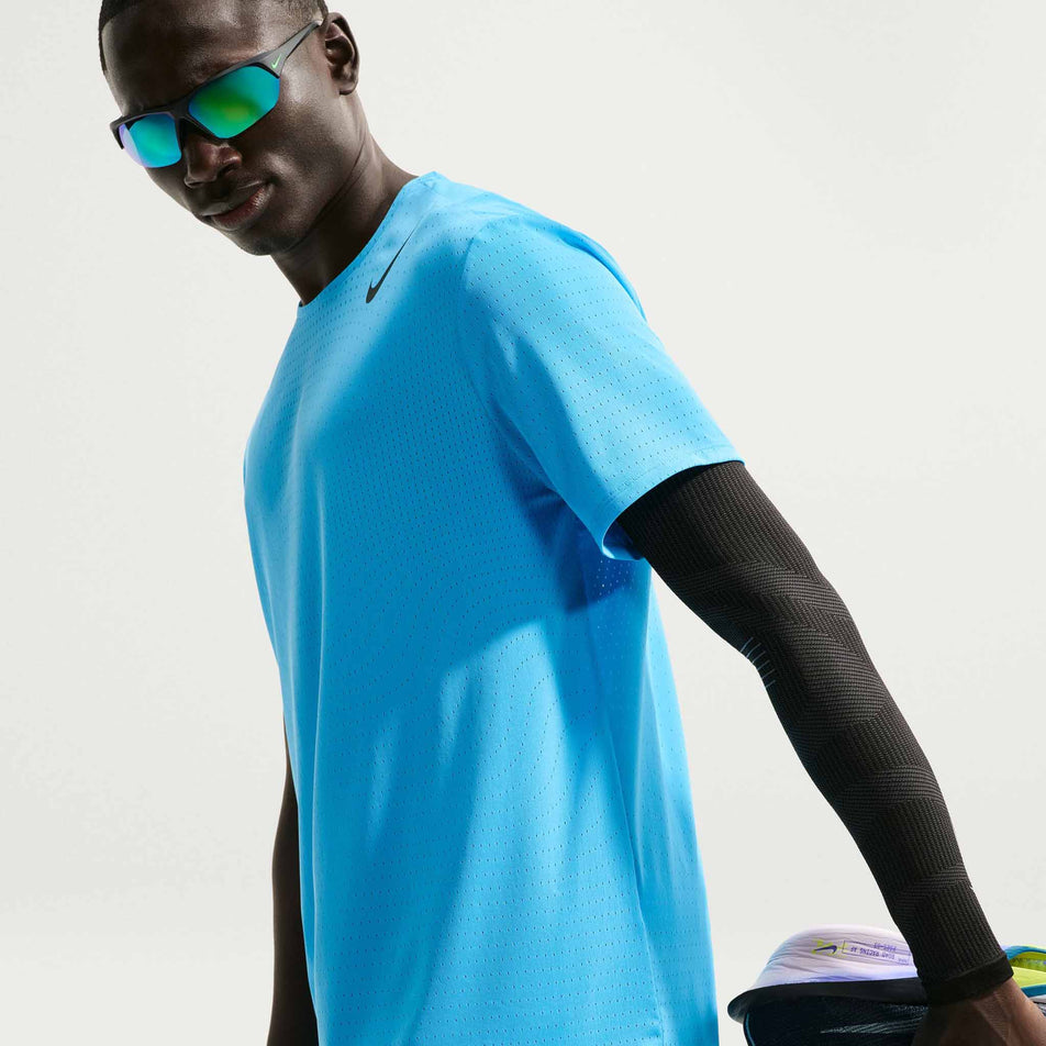 Angled view of a model wearing the Nike Men's AeroSwift Dri-FIT ADV Short-Sleeve Running Top in the Light Current Blue/Black colourway.