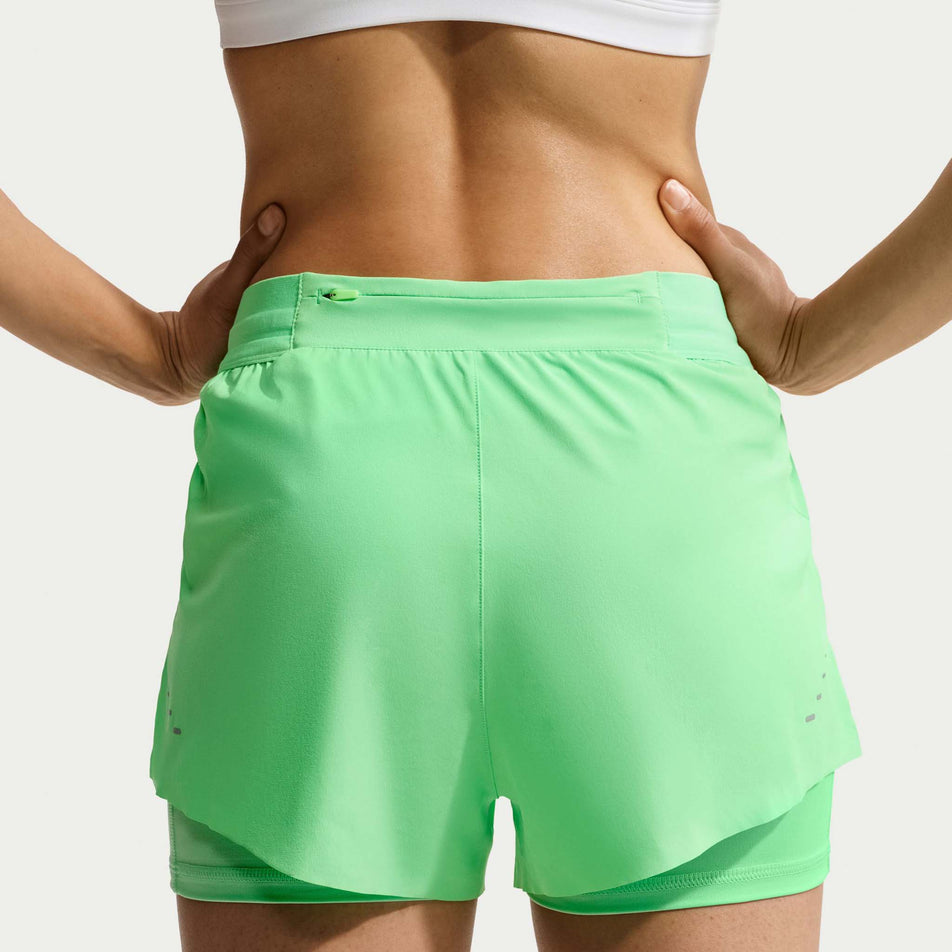 Back view of a model wearing the Nike Women's Swift Dri-FIT Mid-Rise 2-in-1 Running Shorts in the Illusion Green colourway.