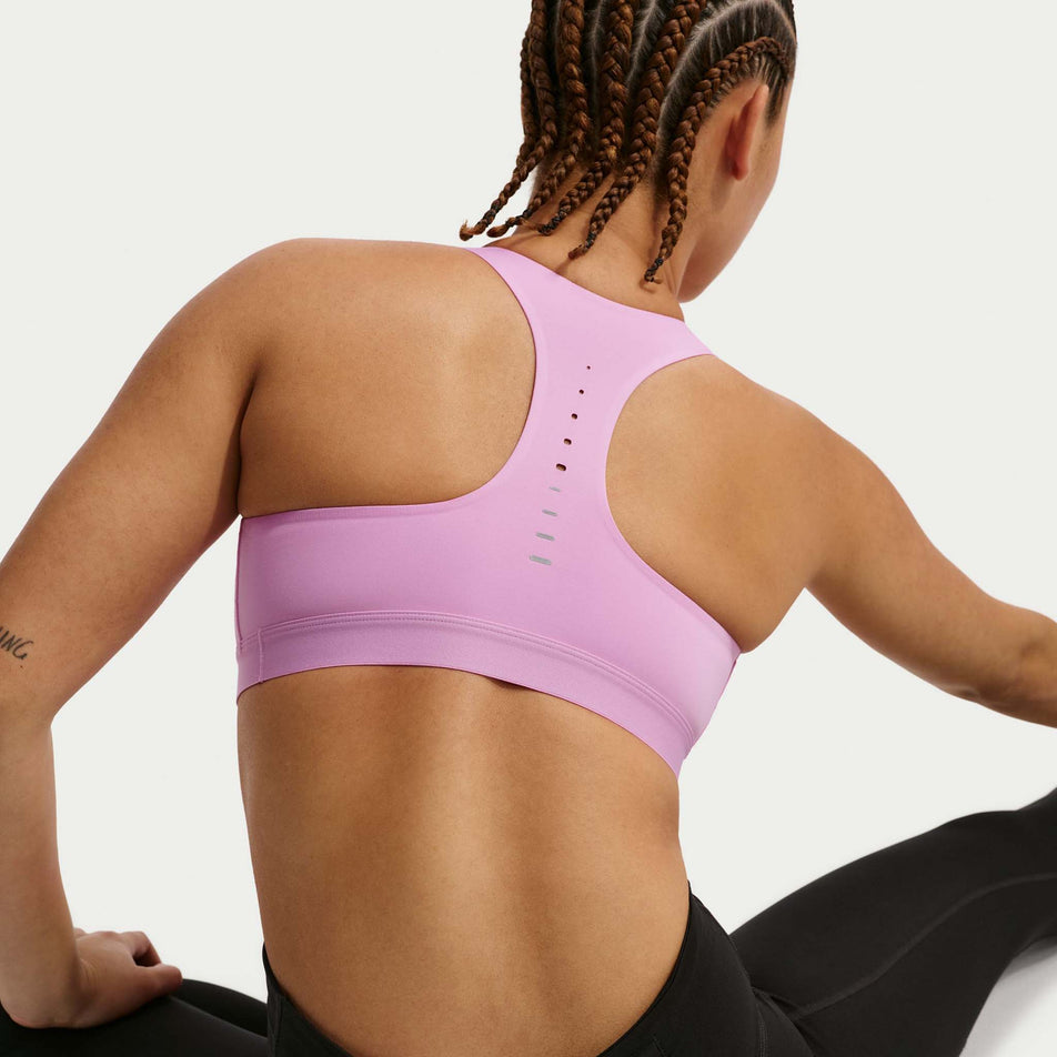 Back view of a model wearing the Nike Women's Swift High-Support Lightly Lined Sports Bra in the Light Magenta/Reflective Silver colourway.