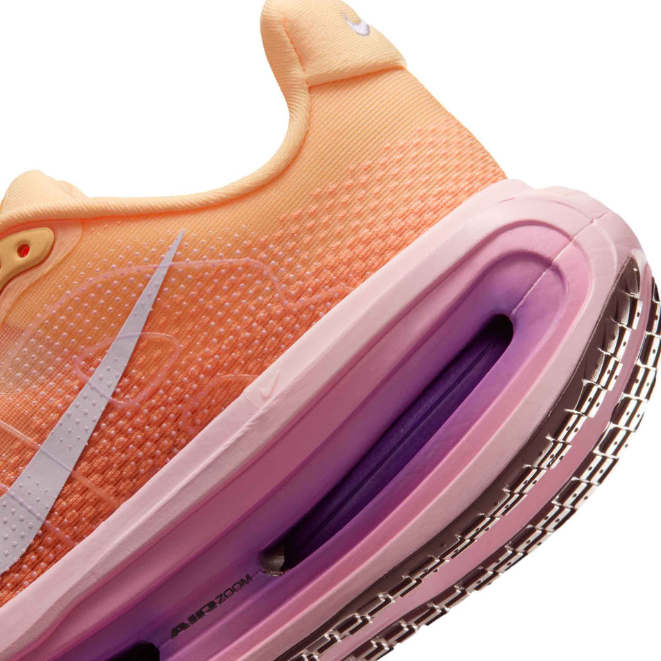 Close-up view of the rearfoot section of the left shoe from a pair of Nike Women's Vomero Premium Road Running Shoes in the Tangerine Tint/Tattoo-Bright Crimson colourway.