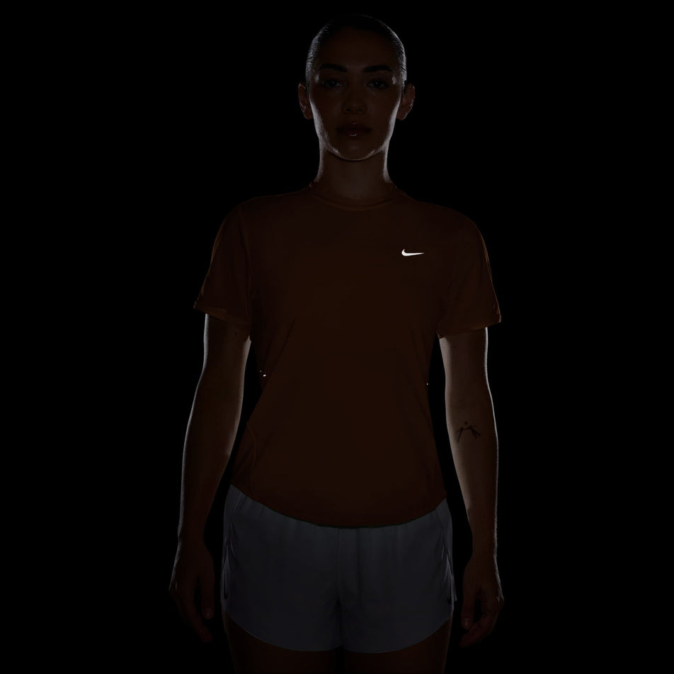 The reflective swoosh on the front of the Nike Women's Swift Dri-FIT Short-Sleeve Running Top in the Orange Pulse/Reflective Silver colourway.