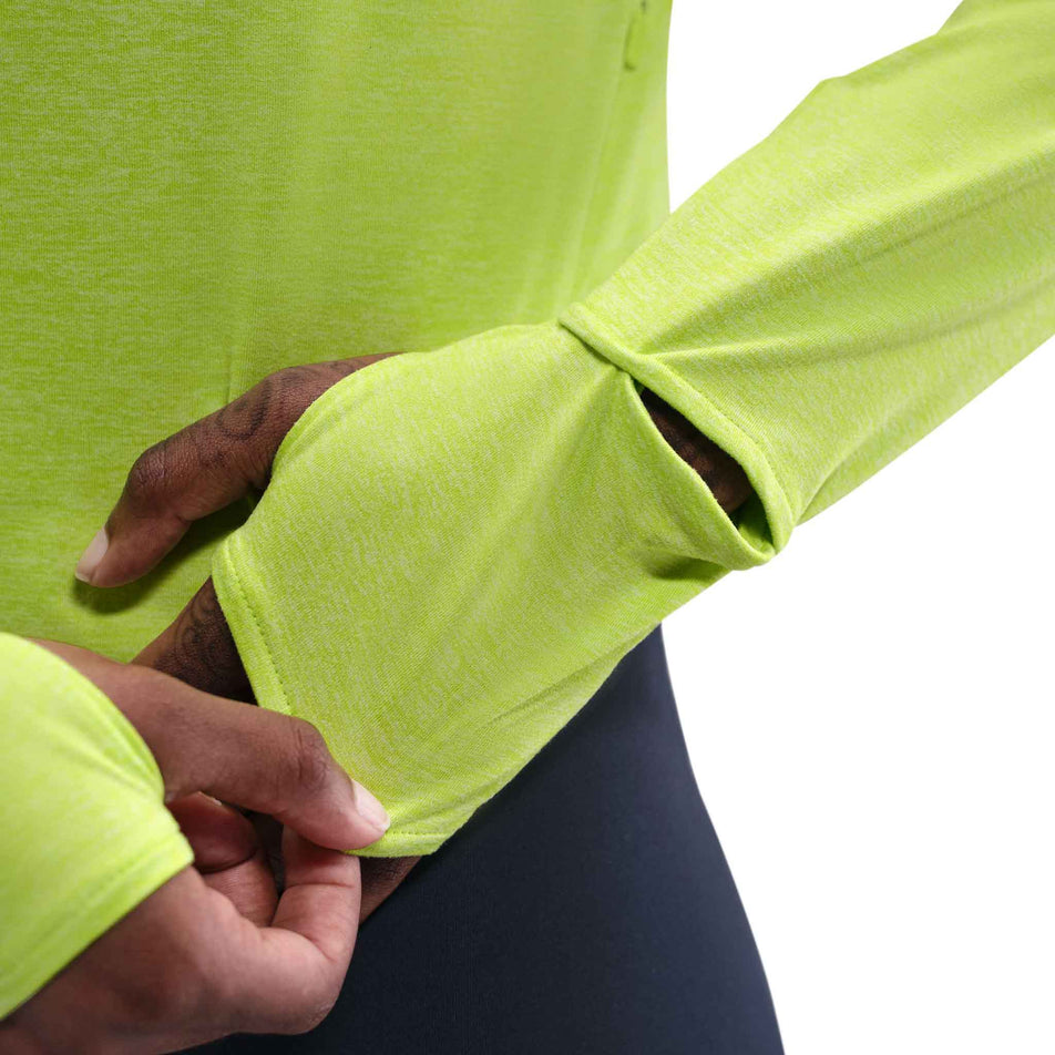 A model demonstrating the thumb loop on the sleeve of the Nike Women's Swift Dri-FIT UV Long-Sleeve Crew-Neck Running Top in the Cyber/Heather/Reflective Silver colourway. (8756573110434)
